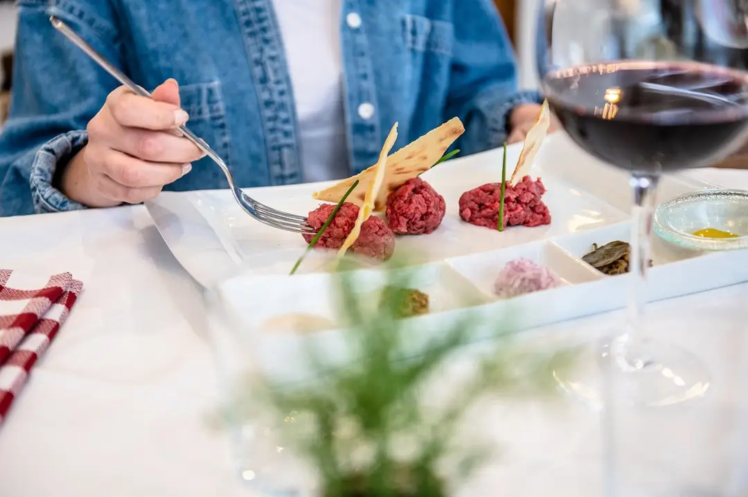 Una persona gusta un pasto a base di tartare di carne e verdure al Ristorante Pizzeria Gustèo in centro a Jesolo