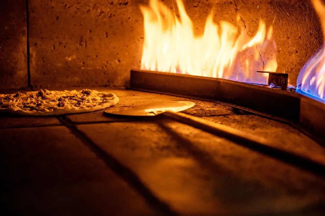 Foto di una pizza che si cucina dentro ad un forno